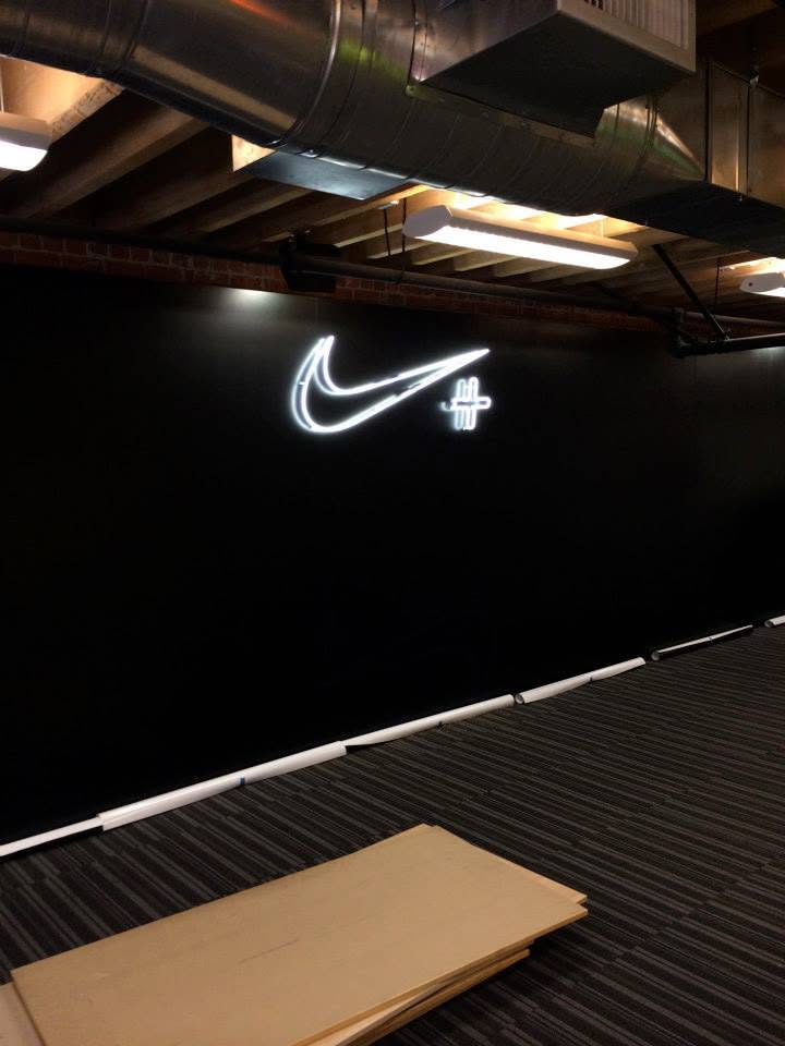 A black wall with a glowing white Nike Swoosh