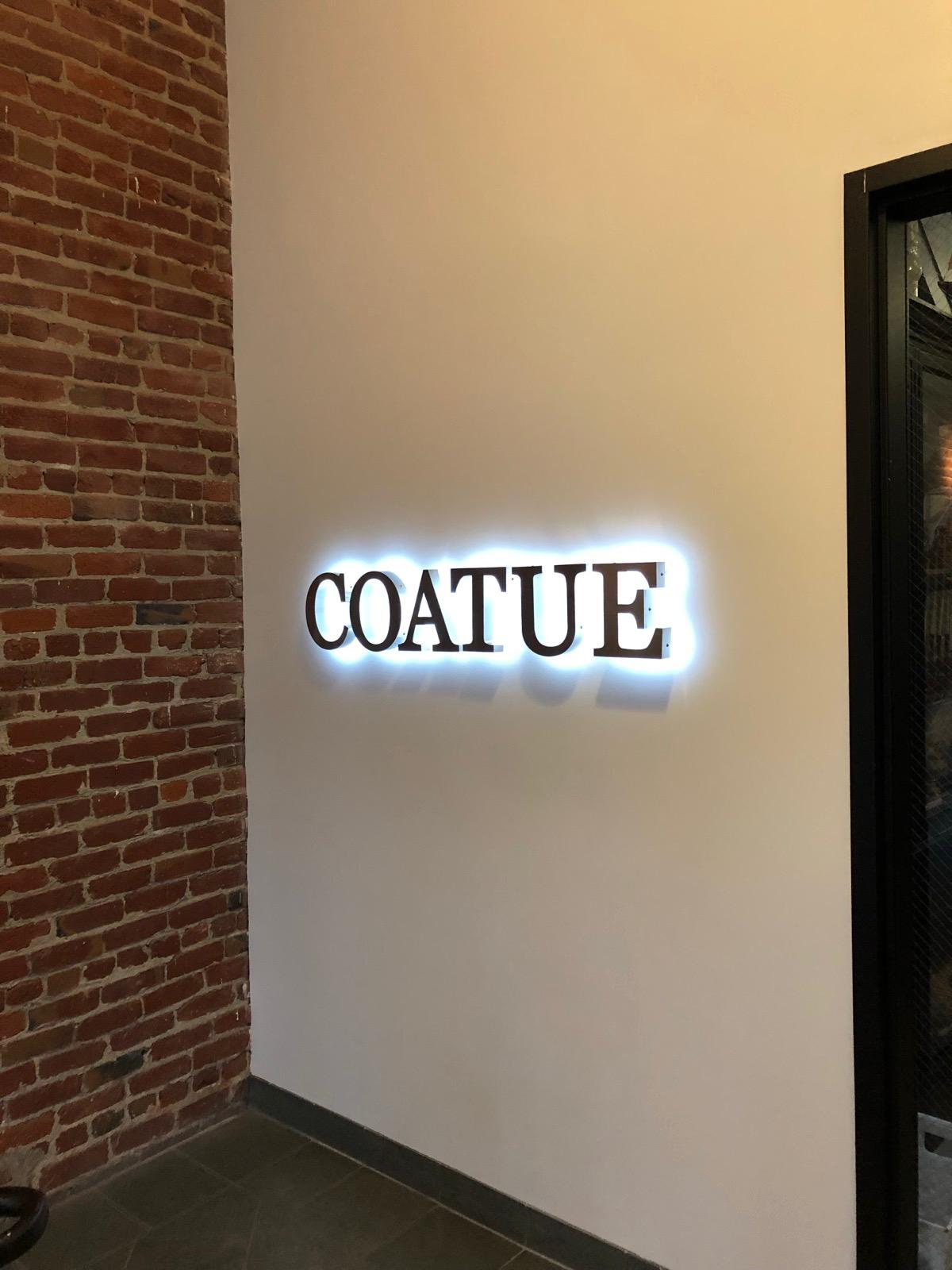 A lit wall sign reading COATUE