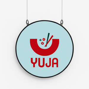 Round sign with red 'Yuja' logo on a light blue background