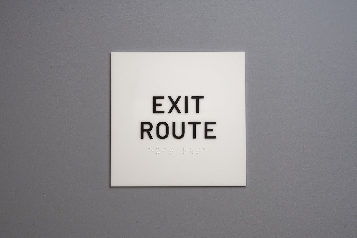 White sign with 'EXIT ROUTE' text on a gray wall
