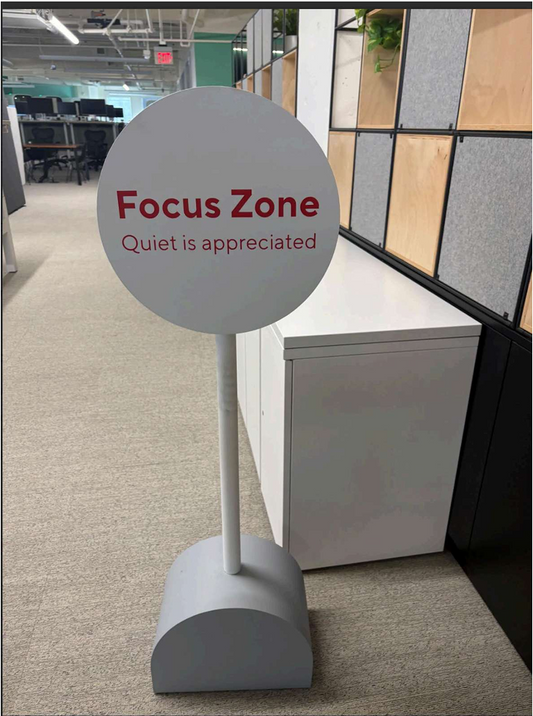 Gray sign with 'Focus Zone Quiet is appreciated' text in an office setting